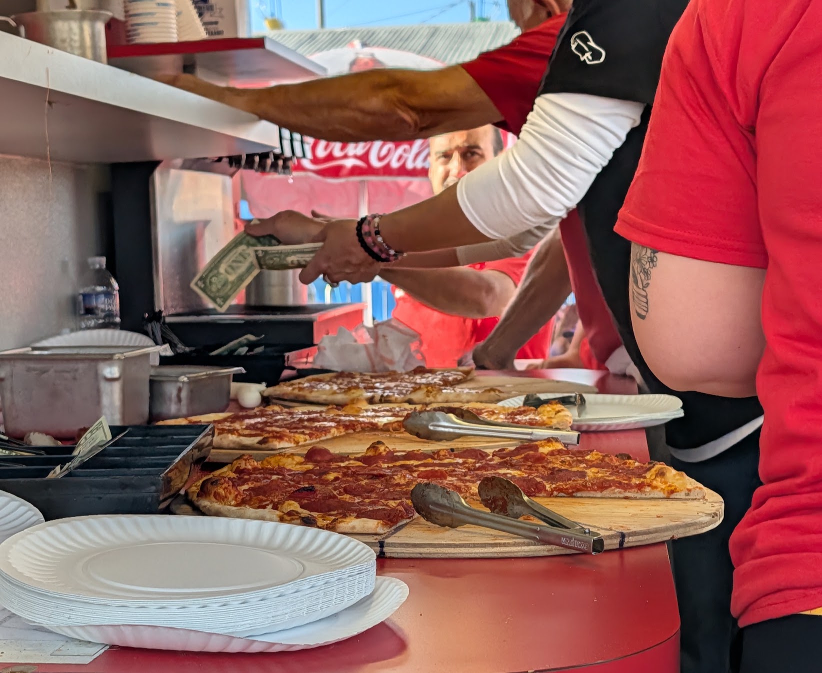 Cash changes hands at the Grotto Pizza stand and workers hand over slices of pizza on opening day of the Bloomsburg Fair in northeastern Pennsylvania. Grotto has grown into a regional brand with restaurants well beyond Bloomsburg, but the fair stand still draws a line on day one and that line will be constant for the next eight days.